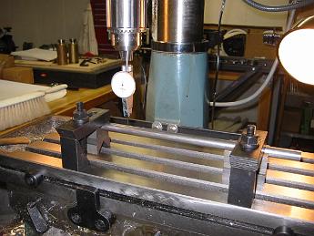 17-Nov-02  I discovered the spur shaft provided by the locomotive company was off-spec.  Way off.  One-half inch short and when the tolerances are in the thousanth of an inch, that spur shaft is not even close.  So here I am clamping the shaft to the Mill table and using a dial indicator making sure the shaft is parallel so I can machine a slot in each end.